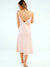 Woman wearing a soft pink linen slip dress standing with her back towards the camera. The slip dress is backless. 
